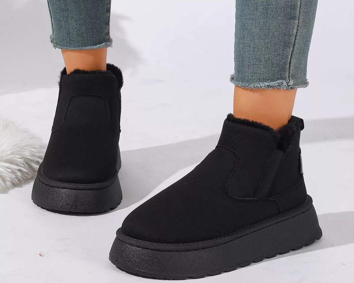 NEWYORKLISTED SHOE COLLECTION: Black platform ankle boots with a fuzzy shearling-style collar, shown on a model wearing blue frayed-hem jeans against a white background.
