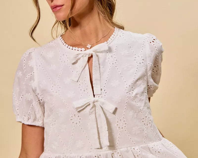NEWYORKLISTED STYLE COLLECTION: Woman wearing a white lace top with a beige background