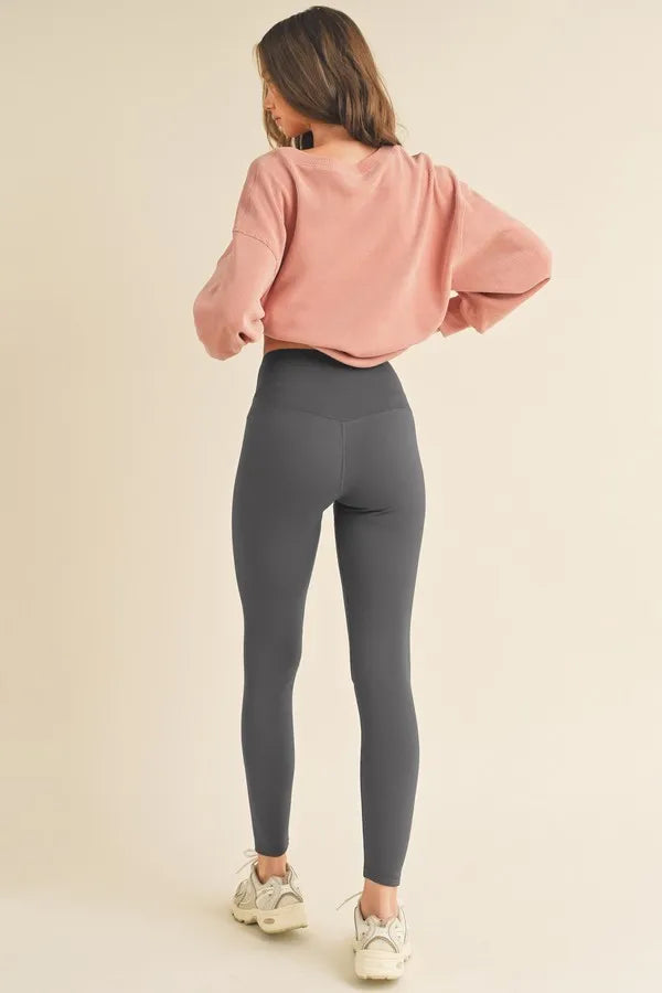 NEWYORKLISTED ACTIVEWEAR Person wearing a pink sweatshirt and gray leggings on a beige background