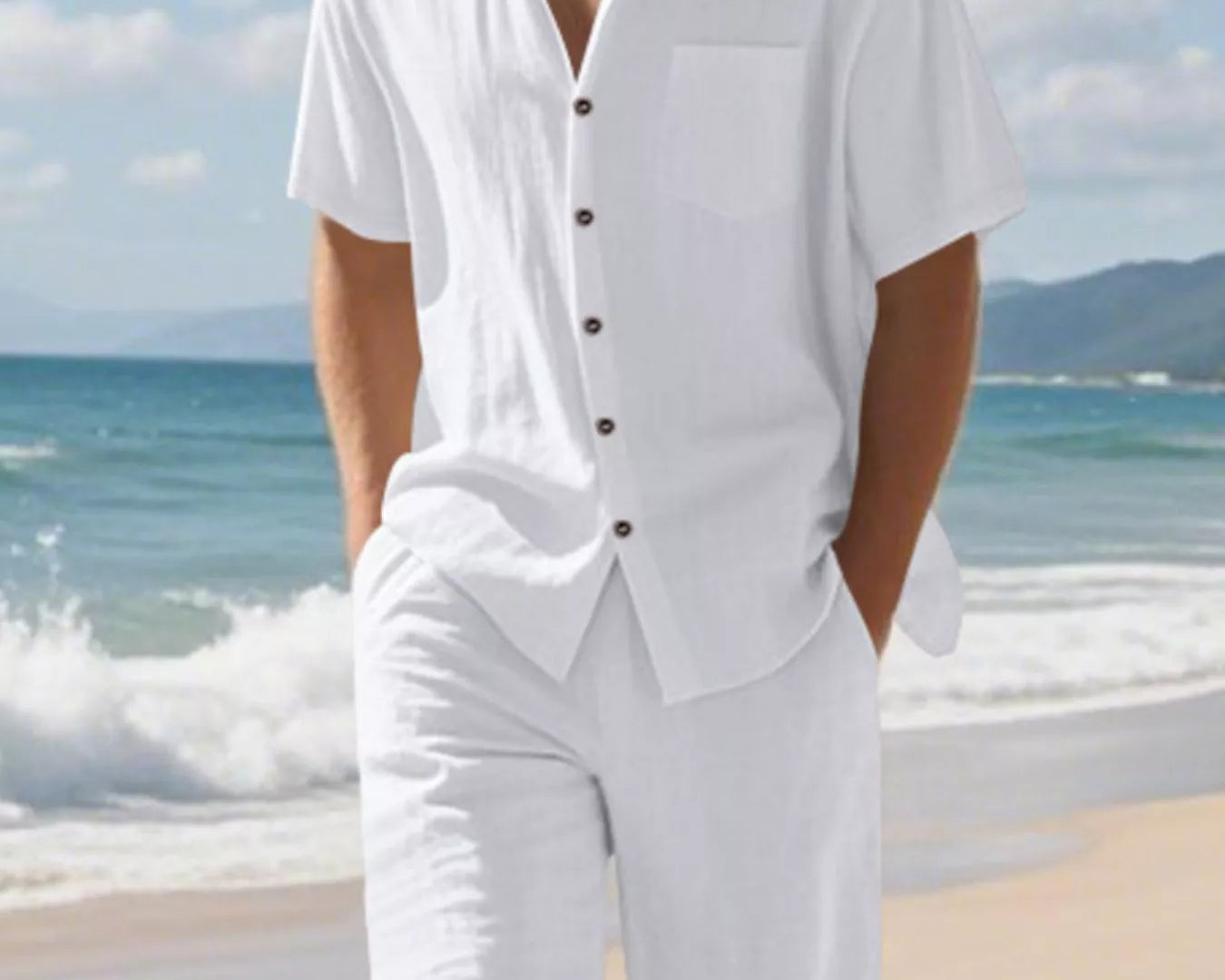NEWYORKLISTED ATLAS MEN'S COLLECTION: Man wearing a white outfit with a button-up shirt and shorts on a beach.