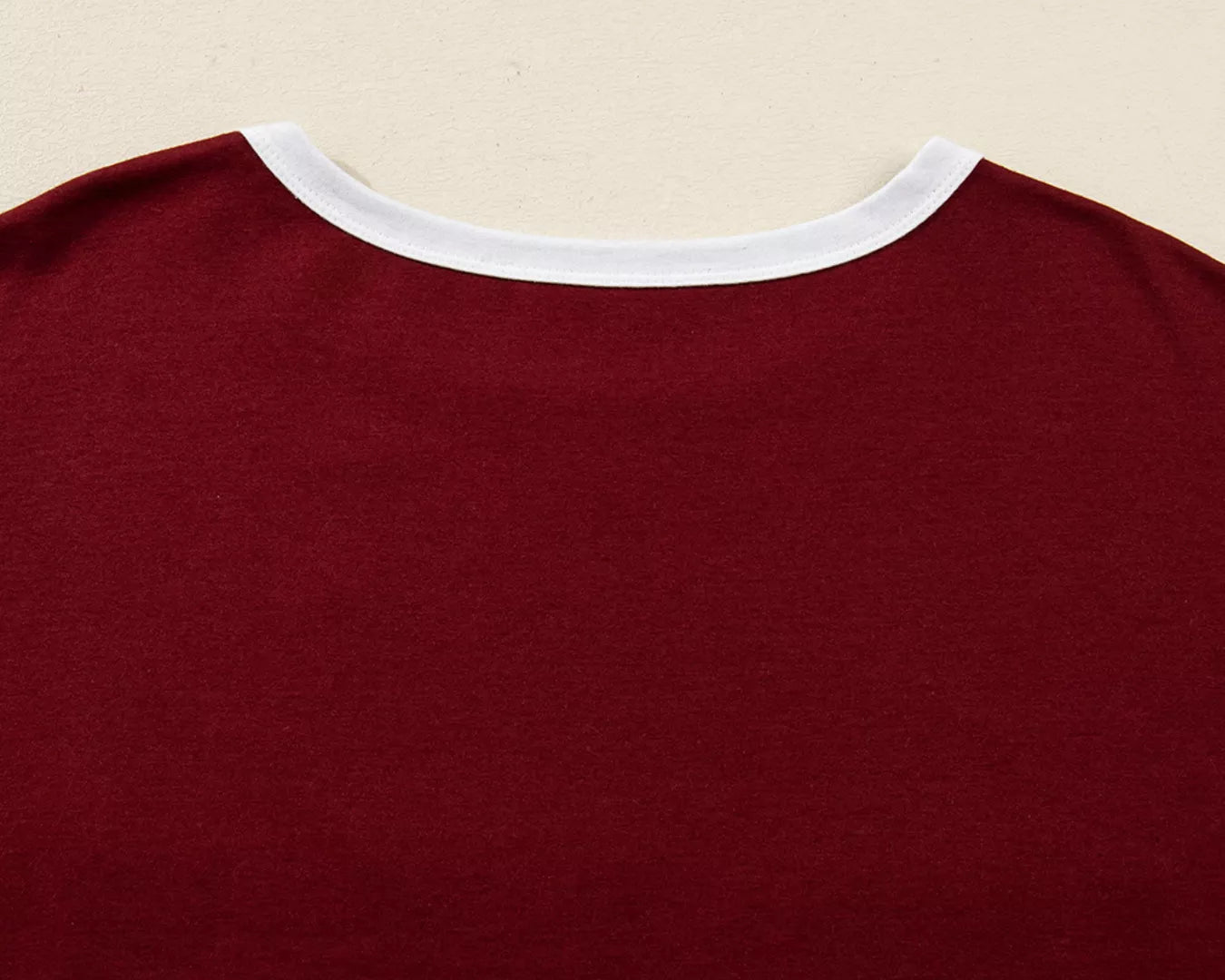 Close-up of a maroon shirt with white trim on a beige background