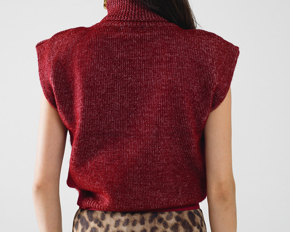 Person wearing a red sleeveless sweater and leopard print skirt with a beige hat on a white background