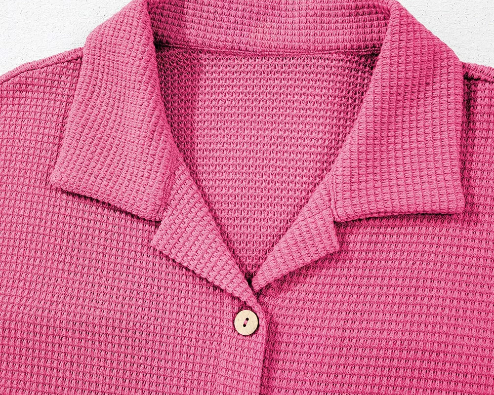 NEWYORKLISTED Comfort Collection: Close-up of a pink textured polo shirt with buttons on a light gray background