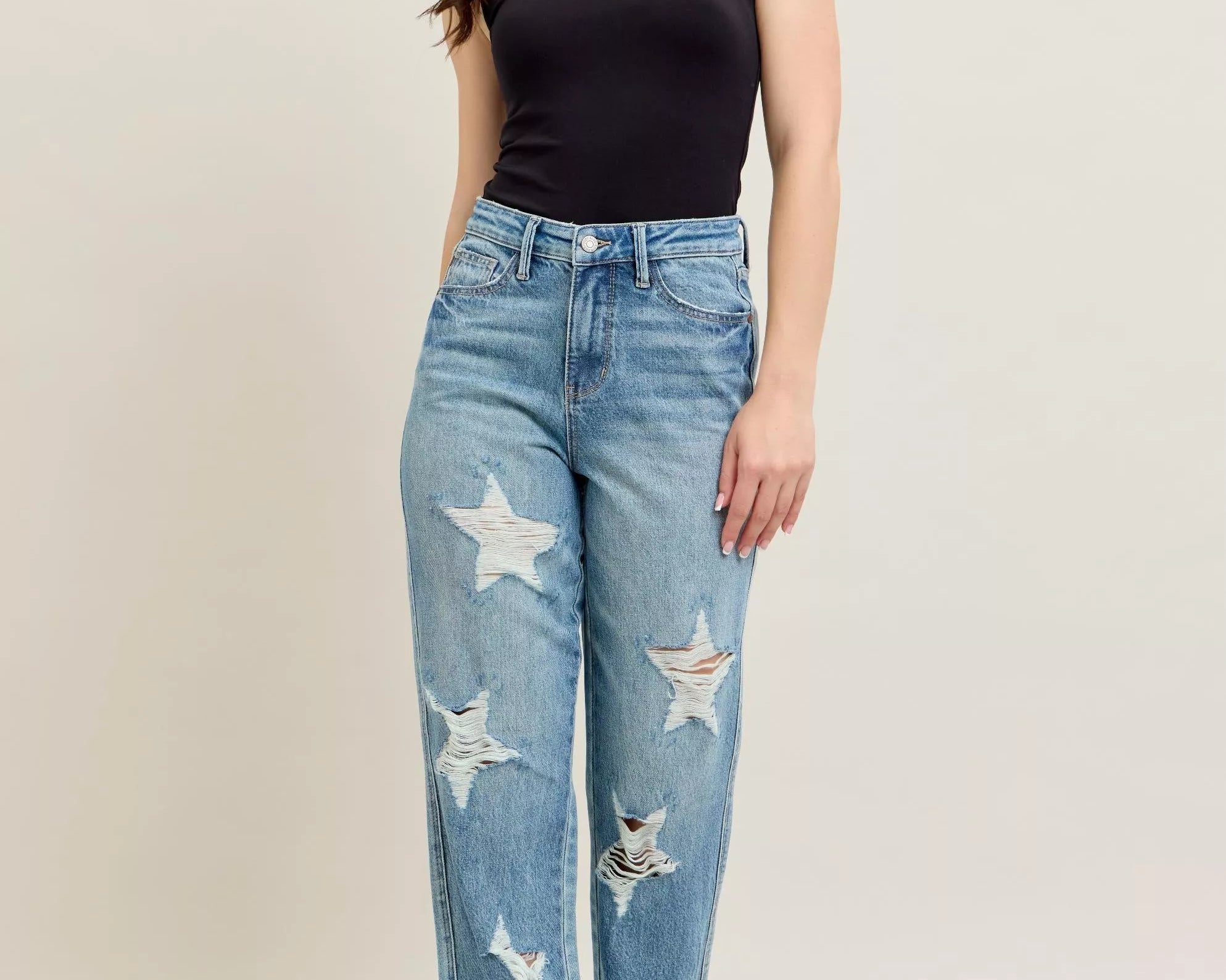 NEWYORKLISTED STYLE COLLECTION: Woman wearing blue jeans with star patterns and a black top on a beige background