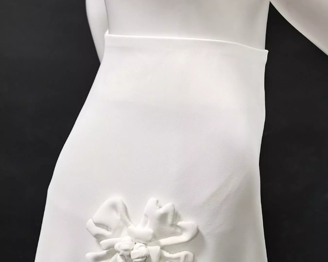 NEWYORKLISTED STYLE COLLECTION: White wedding dress with a decorative flower detail on a black background
