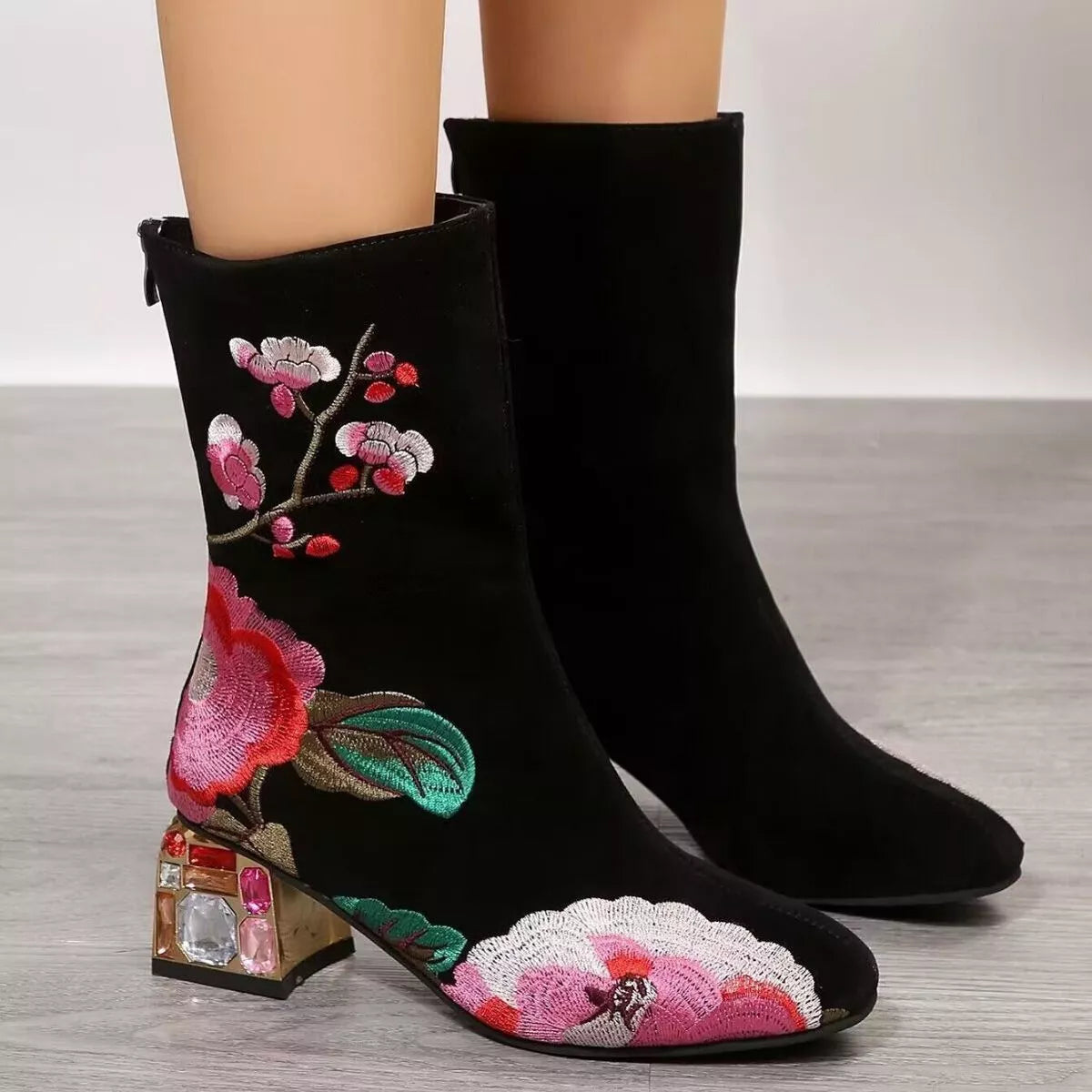 NEWYORKLISTED Shoe Collection: Black ankle boots with floral embroidery on a wooden floor.