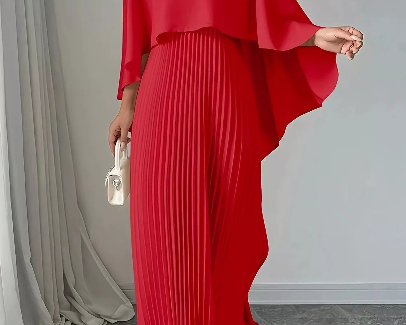 NEWYORKLISTED STYLE COLLECTION: Red pleated dress with cape-like sleeves on a neutral background