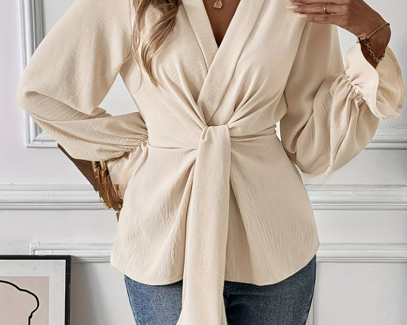 NEWYORKLISTED STYLE COLLECTION: Woman wearing a beige wrap blouse with long sleeves in an indoor setting.