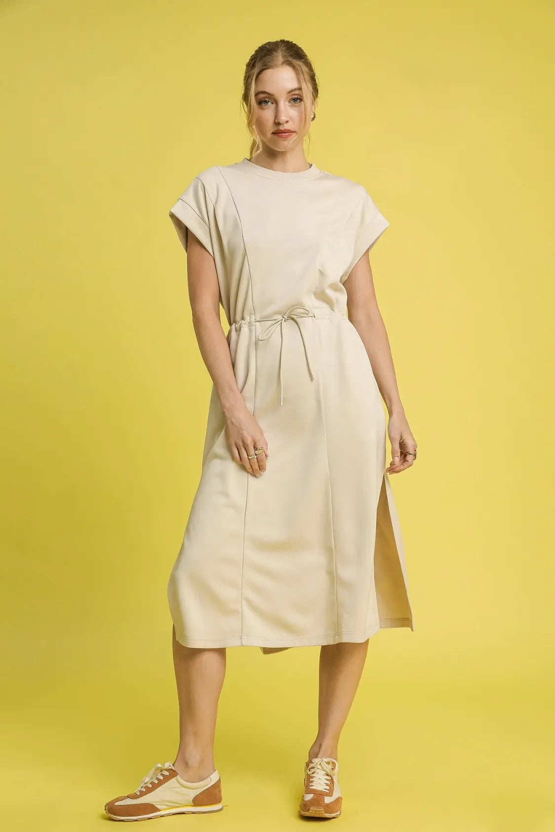 NEWYORKLISTED STYLE COLLECTION: Short Sleeve Midi Tee Dress Woman wearing a beige dress on a yellow background