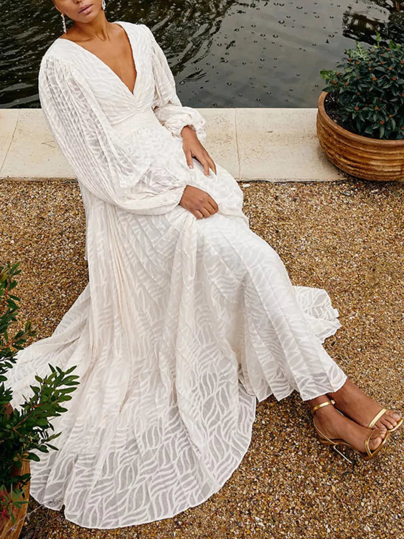 NEWYORKLISTED STYLE COLLECTION: Woman in a white lace dress sitting outdoors near a body of water.