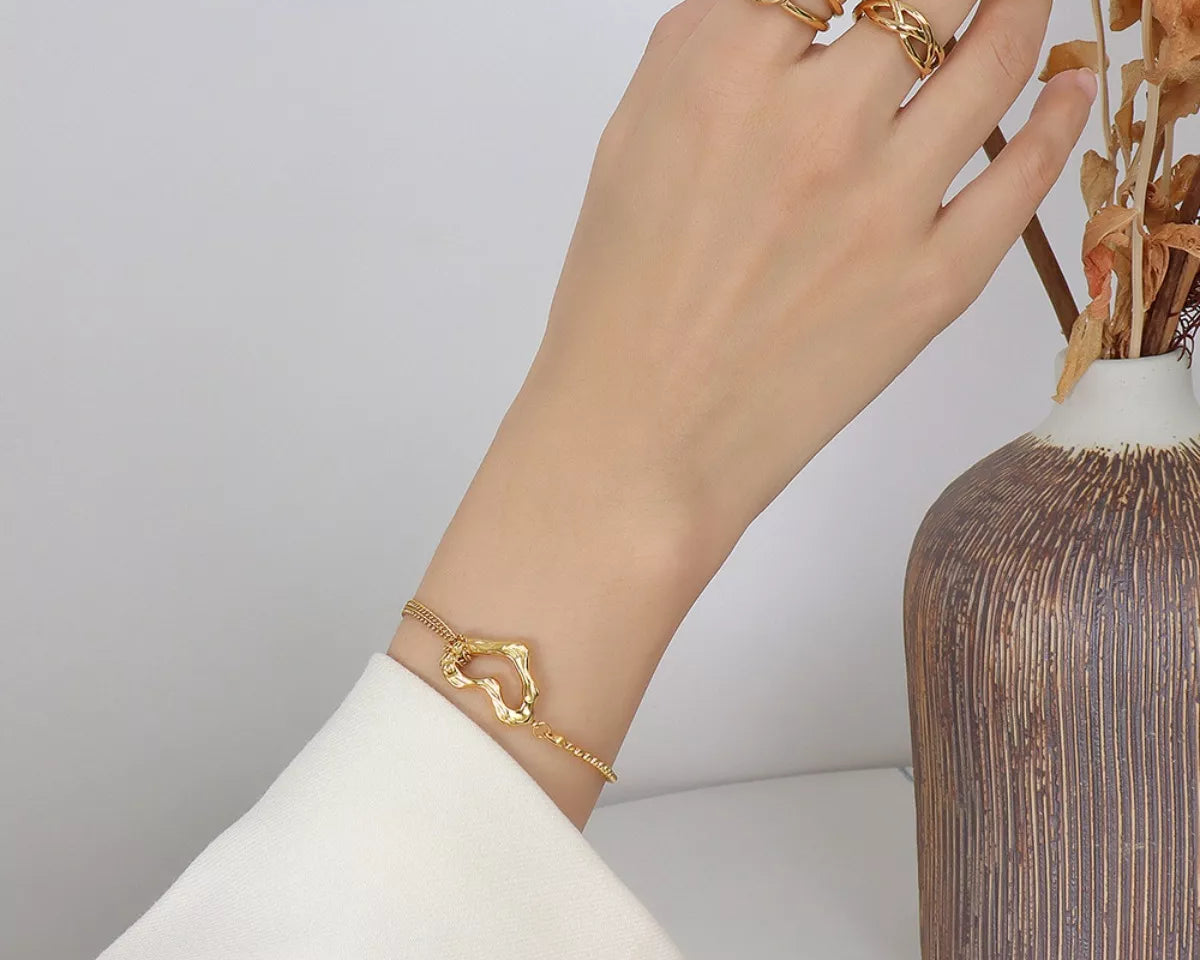 NYLD Glamour Collection by NEWYORKLISTED: Hand wearing gold jewelry with a vase in the background