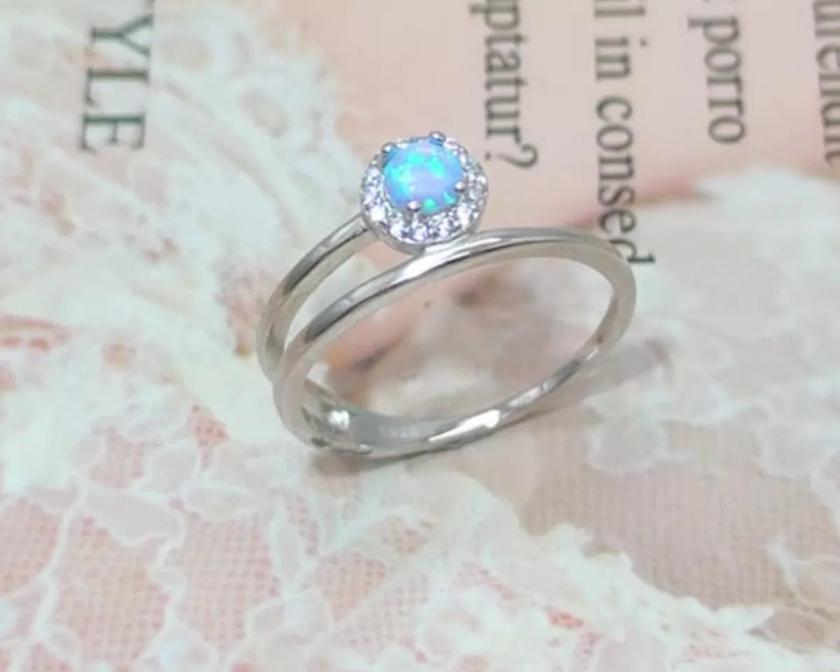 NYLD Glamour Collection by NEWYORKLISTED: Silver ring with a blue gemstone on a textured fabric background