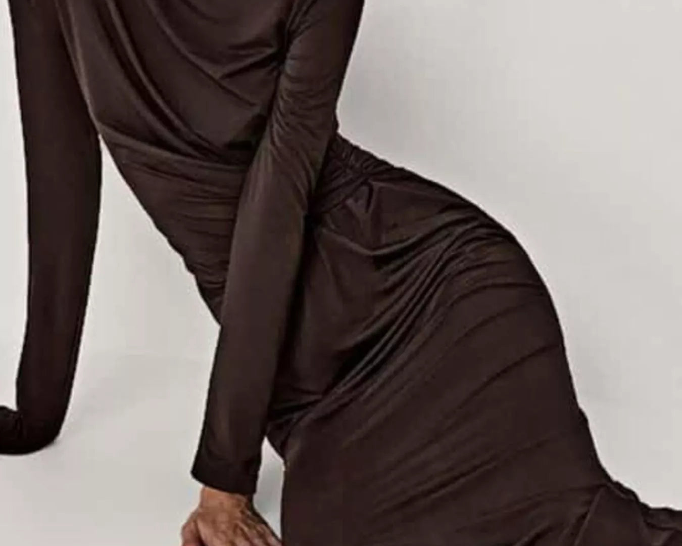 NEWYORKLISTED STYLE COLLECTION: Woman wearing a brown long-sleeve dress sitting on a white background