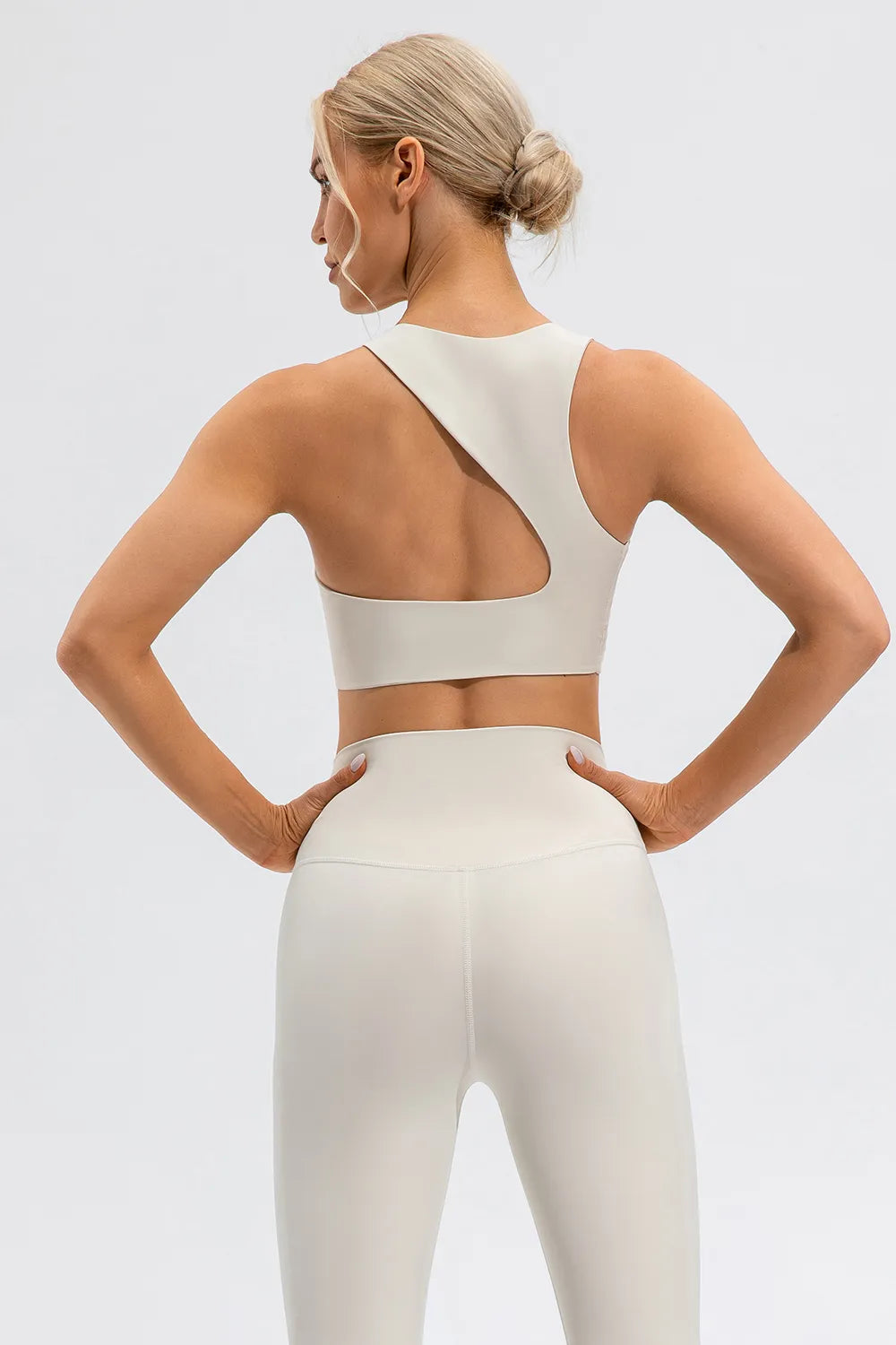 NEWYORKLISTED ACTIVEWEAR COLLECTION: Woman wearing a white sports bra and leggings on a light gray background