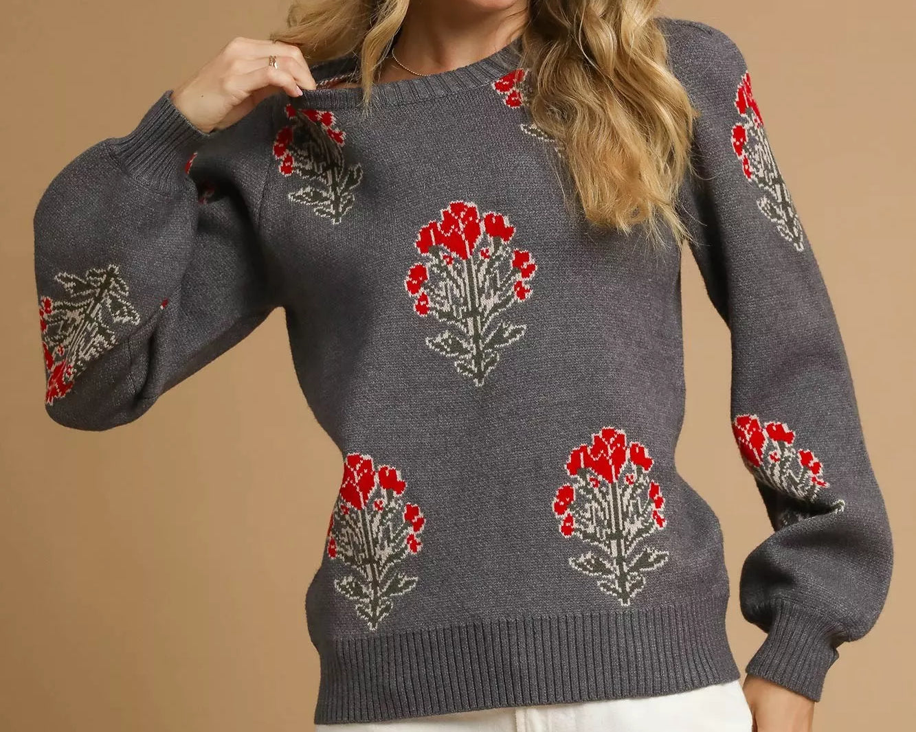NEWYORKLISTED STYLE COLLECTION: Woman wearing a gray sweater with red floral patterns on a beige background