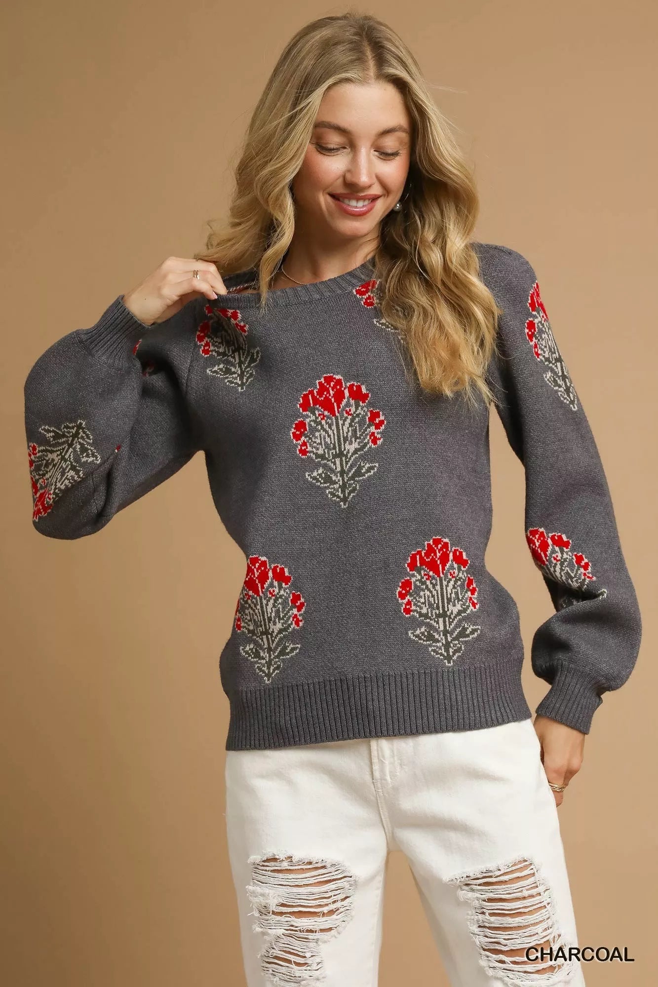NEWYORKLISTED STYLE COLLECTION: Woman wearing a gray sweater with red floral patterns on a beige background