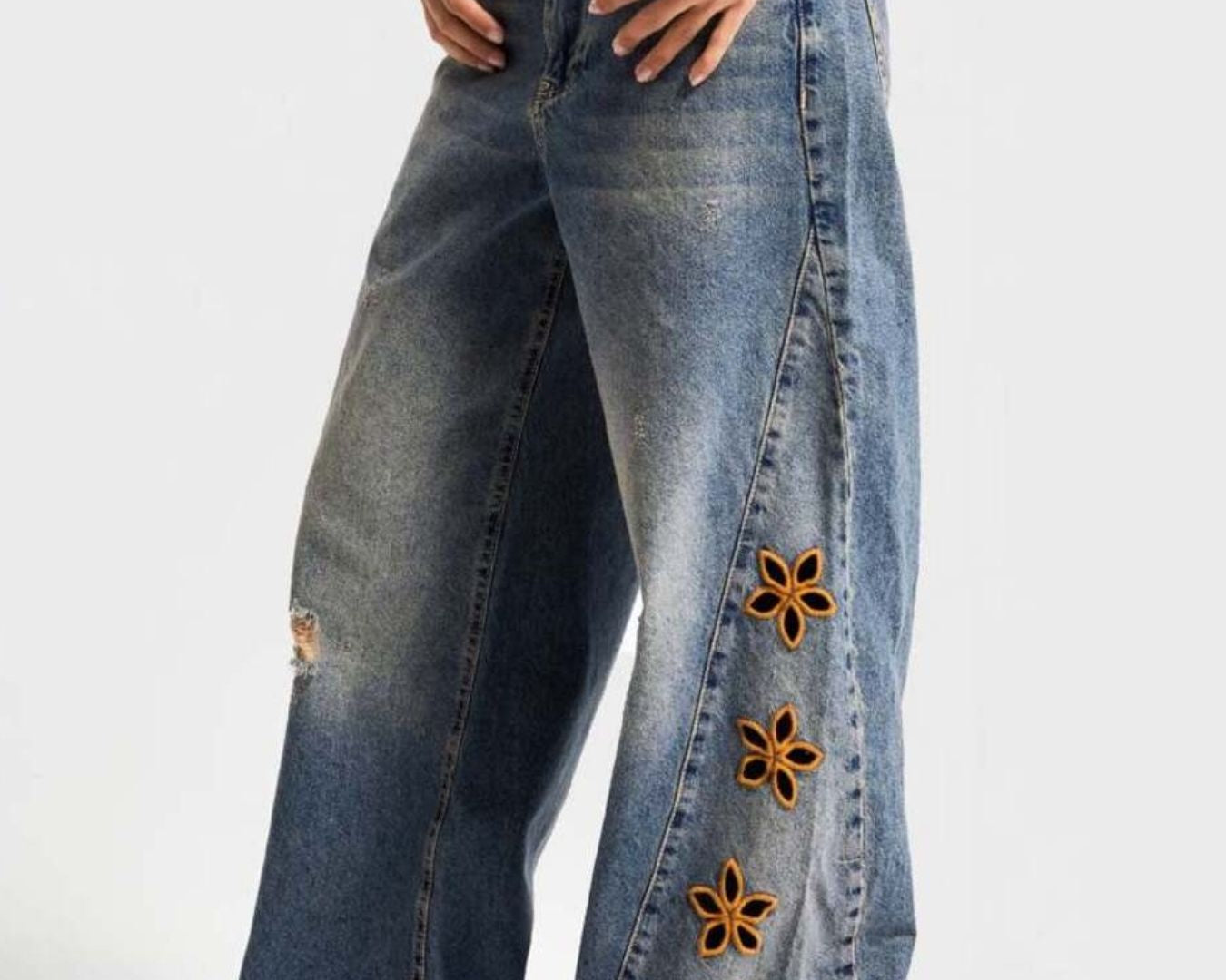 NEWYORKLISTED STYLE COLLECTION: Blue jeans with floral embellishments on a white background