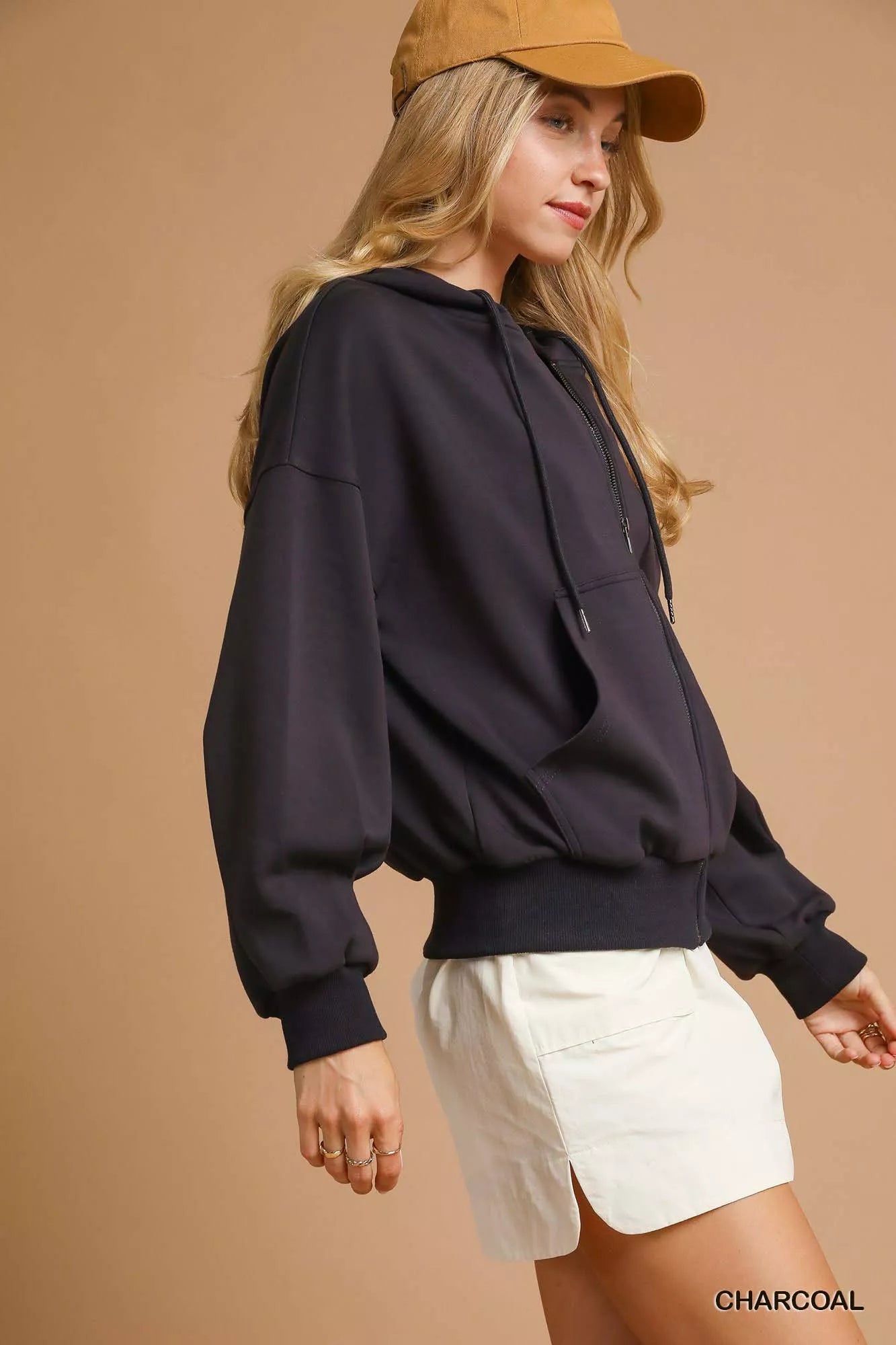 NEWYORKLISTED STYLE COLLECTION: Woman wearing a black hoodie and white shorts against a beige background