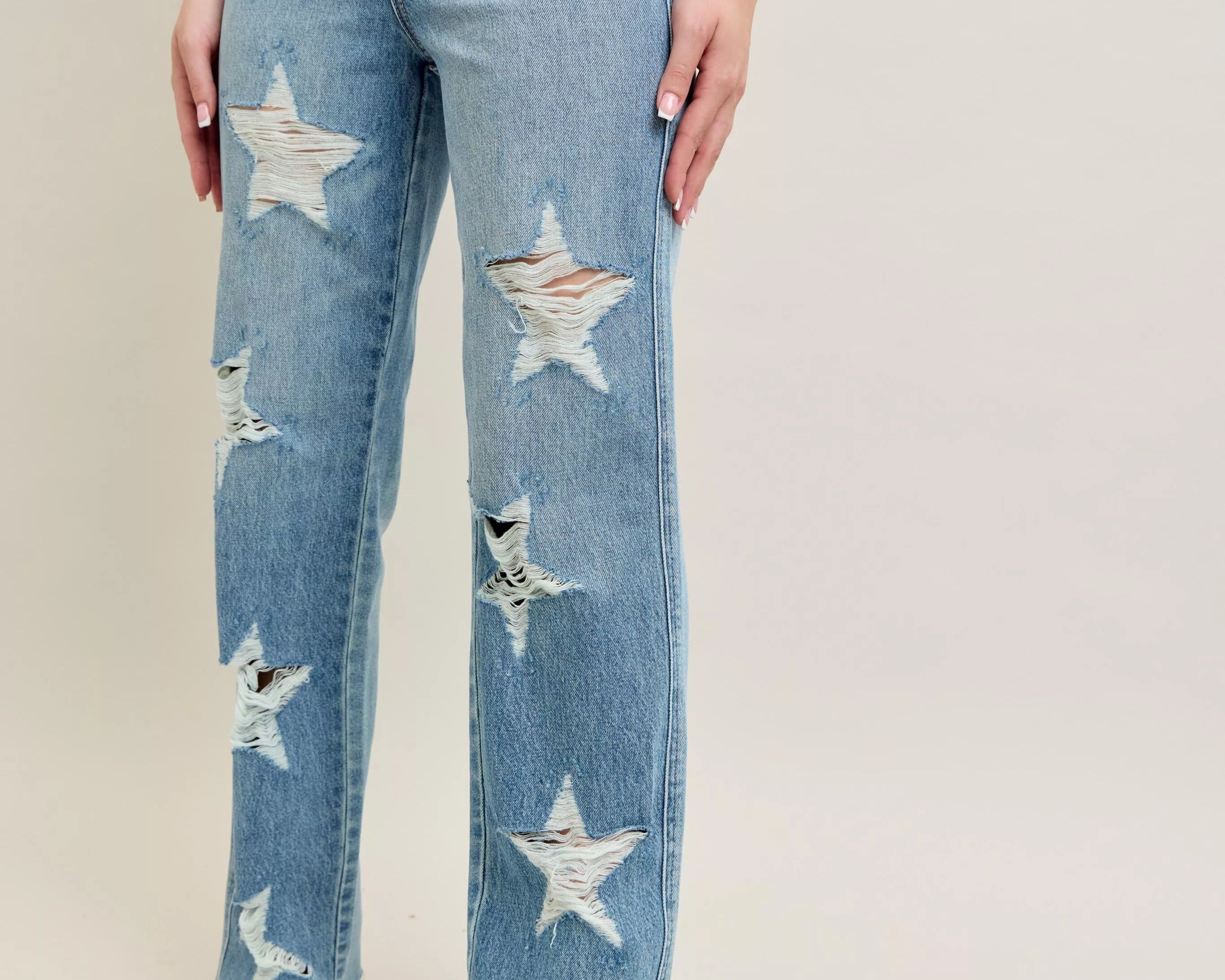 NEWYORKLISTED STYLE COLLECTION: Blue jeans with star patterns worn by a person on a plain background