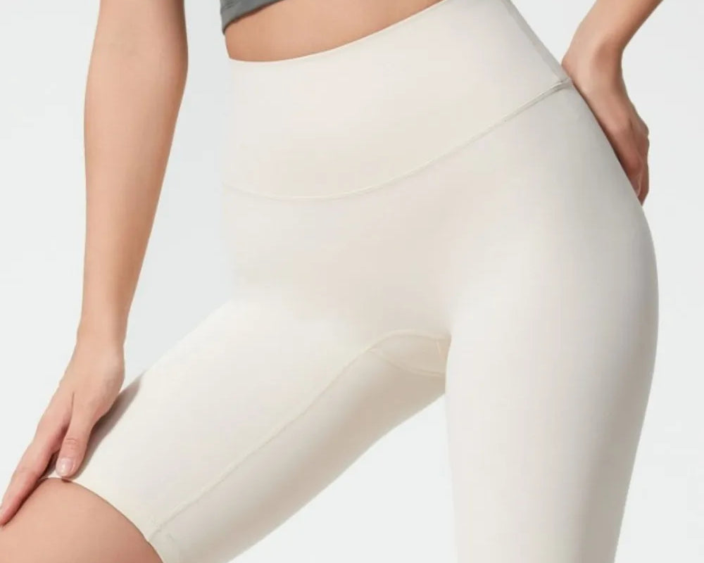 Person wearing beige high-waisted shorts on a plain background