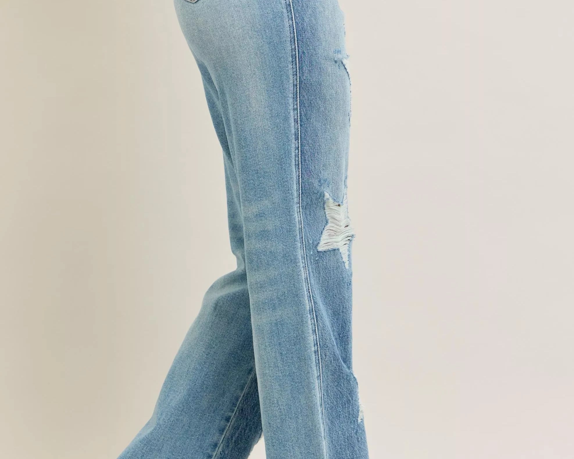 NEWYORKLISTED STYLE COLLECTION: Light blue jeans with a slight distressed look worn by a person on a beige background