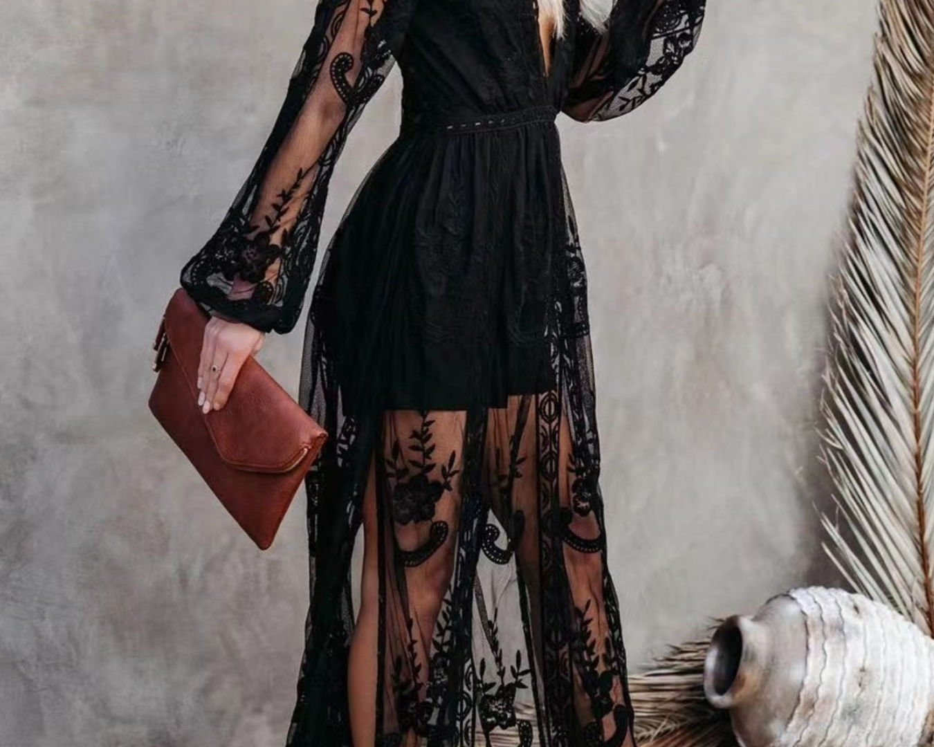 NEWYORKLISTED STYLE COLLECTION: Woman wearing a black lace dress holding a brown clutch against a neutral background