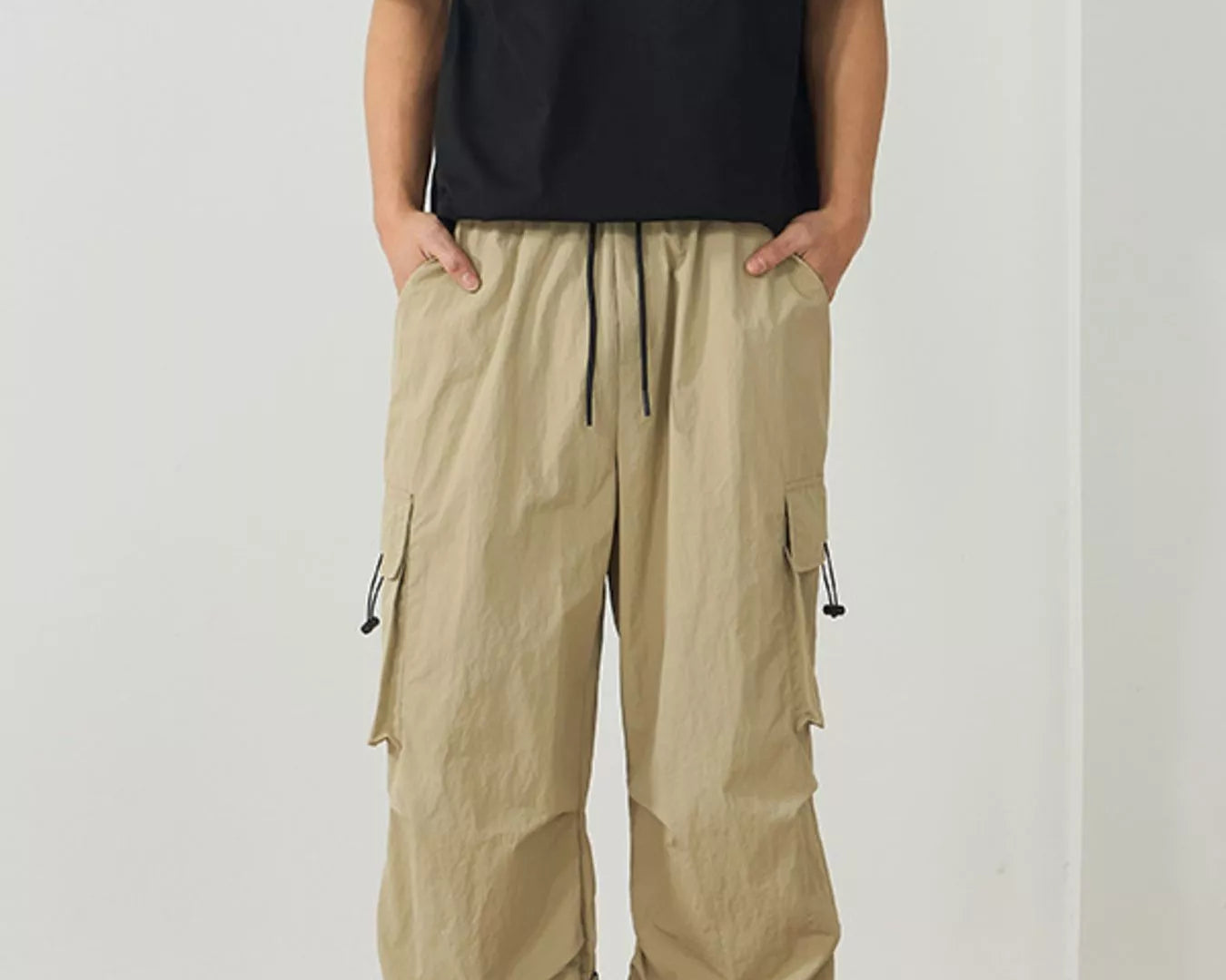 NEWYORKLISTED ATLAS MEN's Collection: Person wearing beige cargo pants and a black t-shirt on a plain background