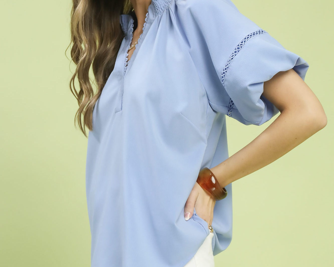 NEWYORKLISTED STYLE COLLECTION: Woman wearing a light blue blouse with short sleeves on a light green background
