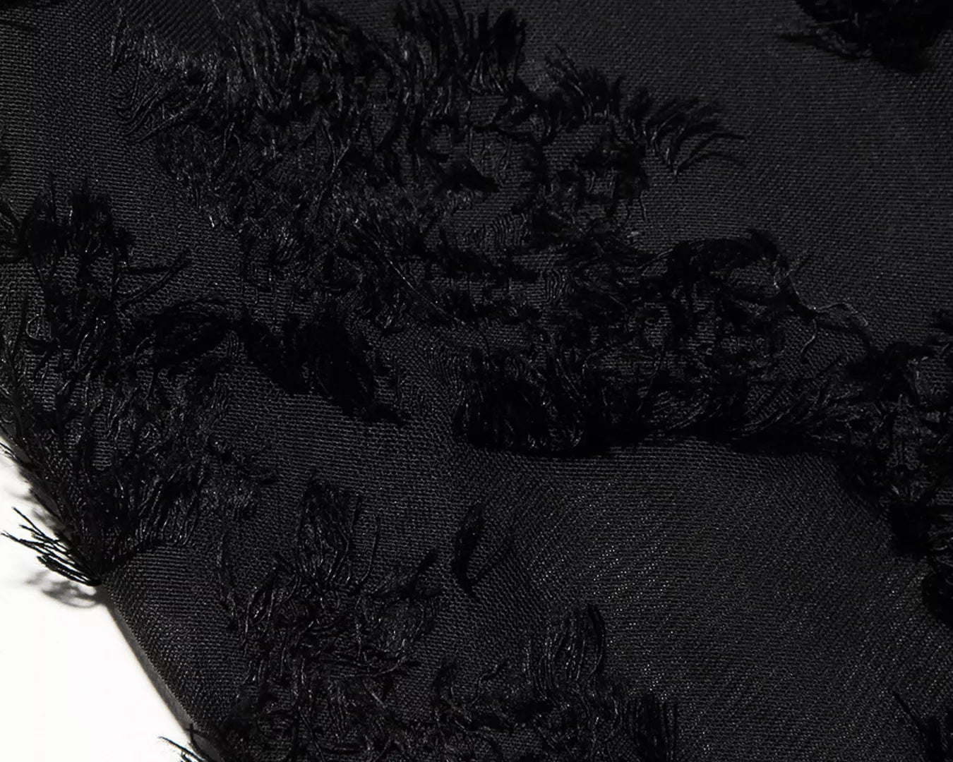 NEWYORKLISTED STYLE COLLECTION: Close-up of black textured fabric with frayed edges on a dark background