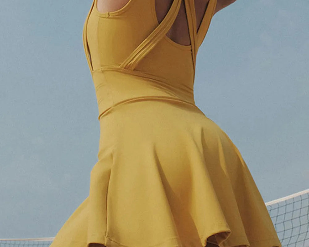 NEWYORKLISTED ACTIVEWEAR COLLECTION: Person wearing a yellow dress on a beach with a clear sky.
