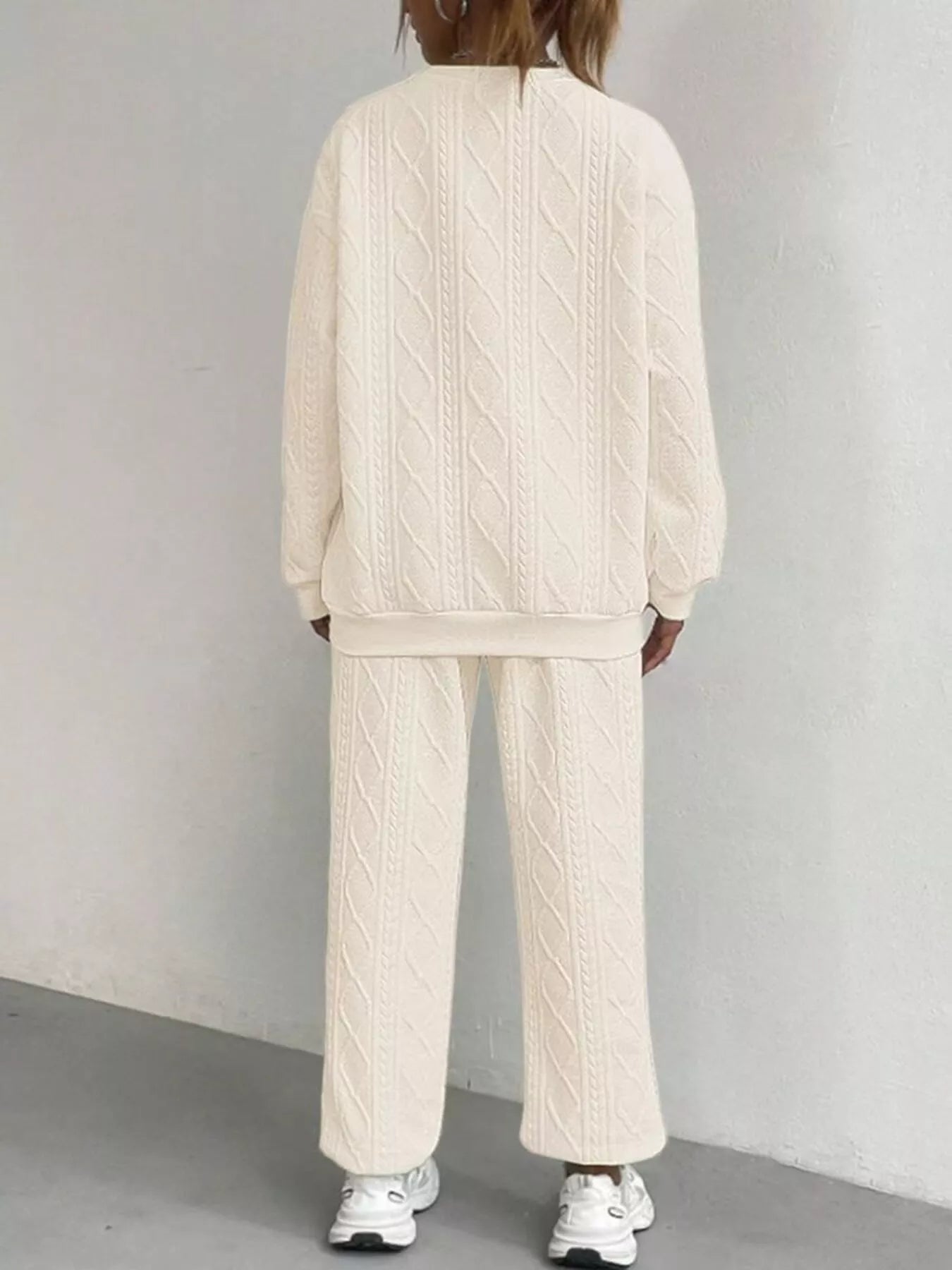 NEWYORKLISTED COMFORT COLLECTION: Person wearing a cream cable knit tracksuit against a plain background