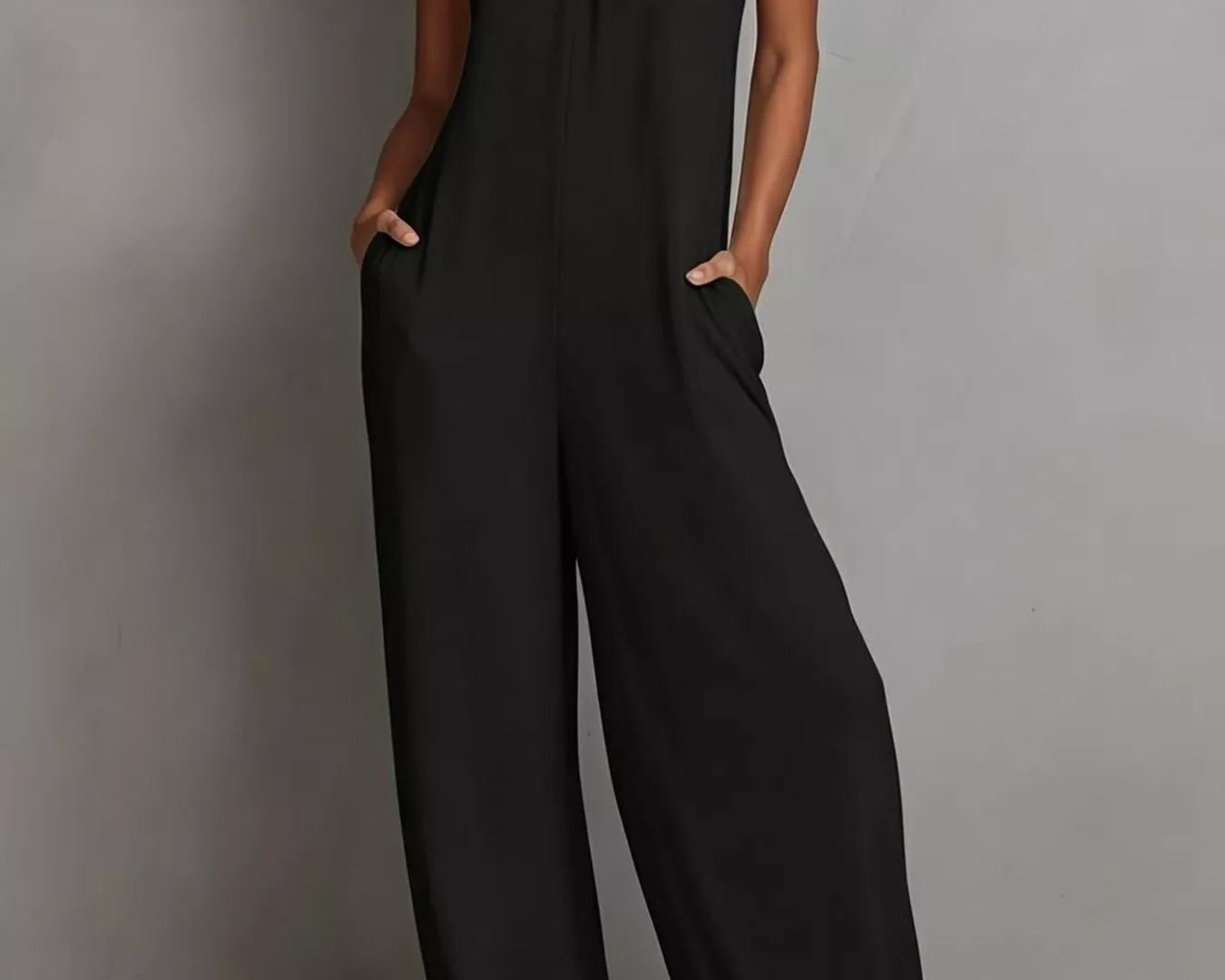 NEWYORKLISTED STYLE COLLECTION: Woman wearing a black jumpsuit against a gray background