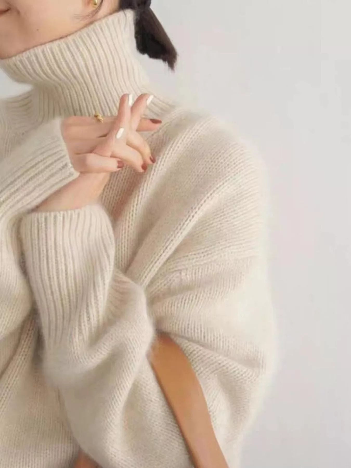 Close-up of a person wearing a beige turtleneck sweater against a white background: NEWYORKLISTED STYLE COLLECTION