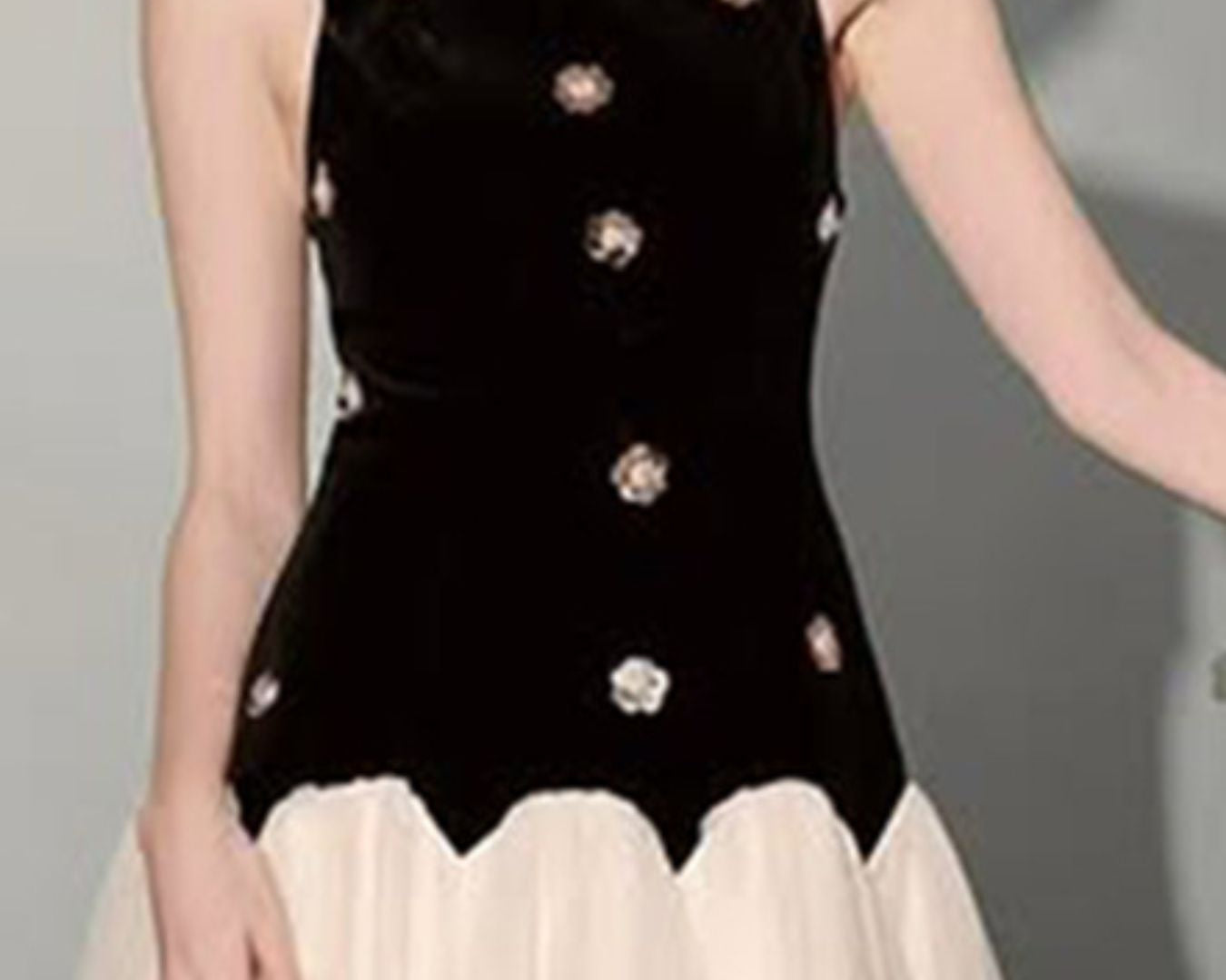 NEWYORKLISTED STYLE COLLECTION: Black sleeveless top with decorative buttons worn by a person on a gray background