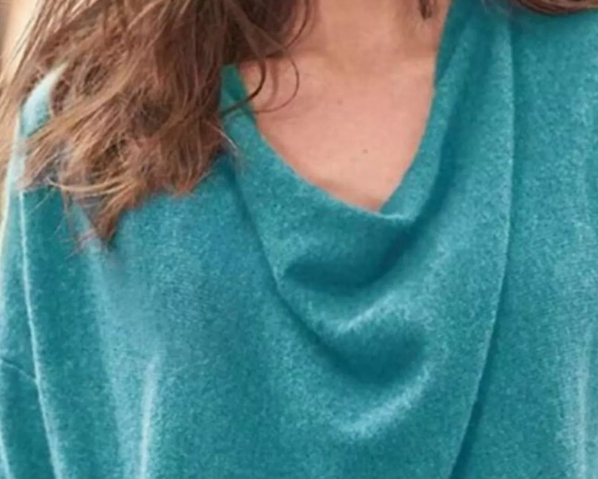 NEWYORKLISTED STYLE COLLECTION: Close-up of a person wearing a teal sweater with a blurred background