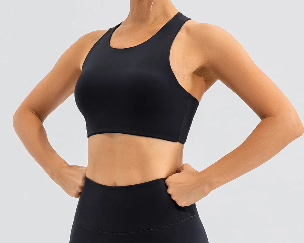 NEWYORKLISTED ACTIVEWEAR COLLECTION: Woman wearing a black sports bra and leggings on a light gray background