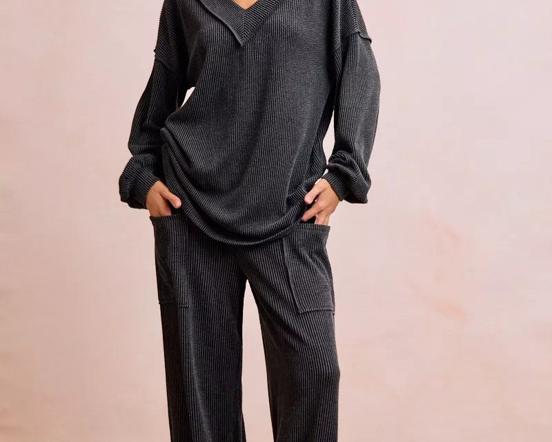 NEWYORKLISTED Comfort Collection: Woman wearing a dark gray outfit with wide-leg pants against a plain background