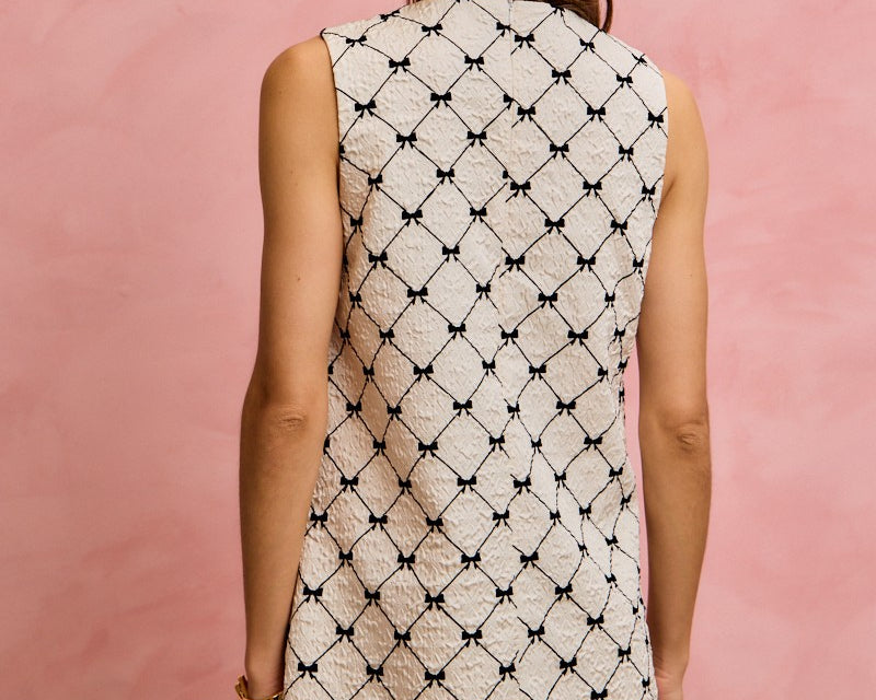 NEWYORKLISTED STYLE COLLECTION: Woman wearing a sleeveless dress with a geometric pattern against a pink background