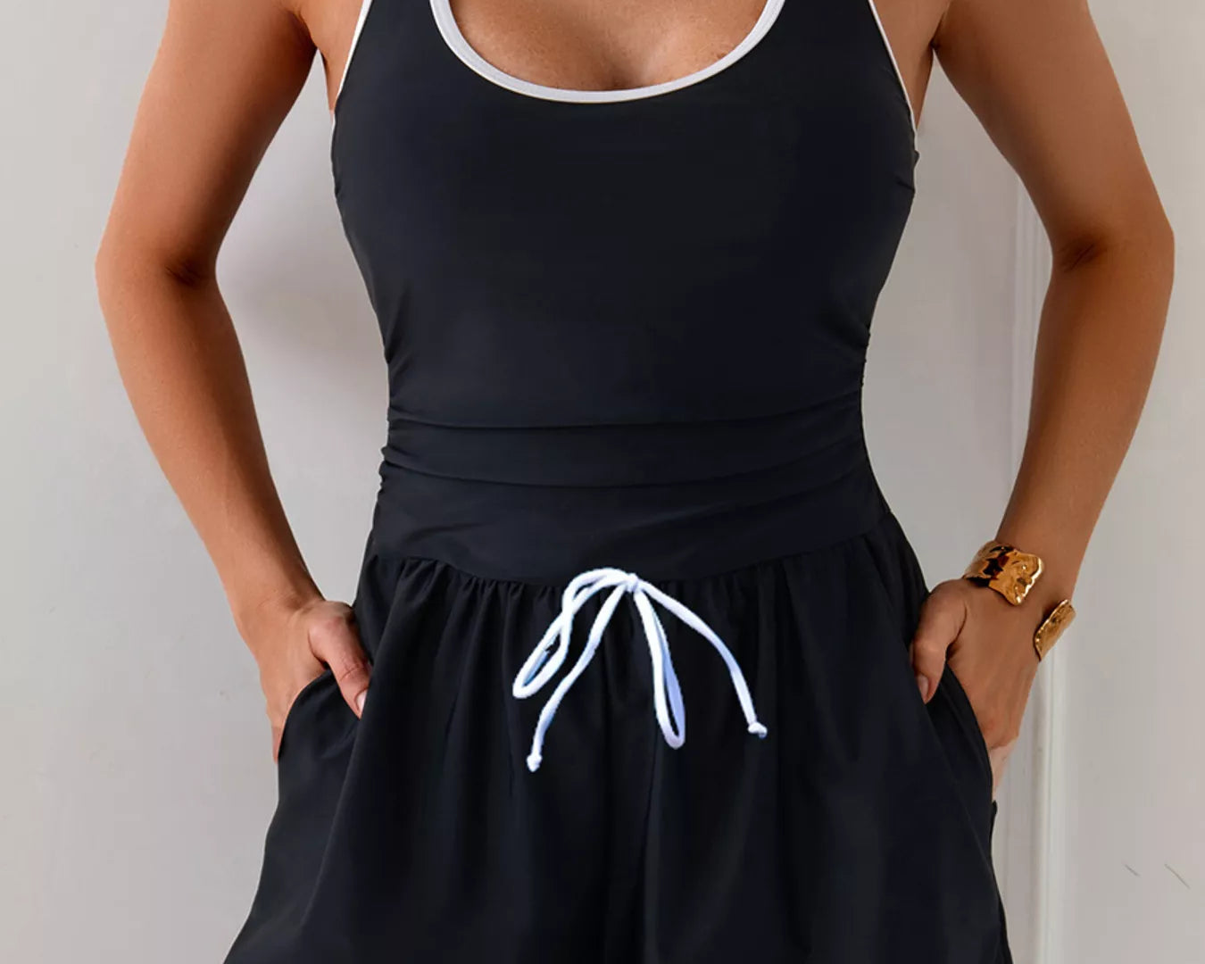 NEWYORKLISTED STYLE COLLECTION: Person wearing a black tank top and shorts with white trim against a plain background