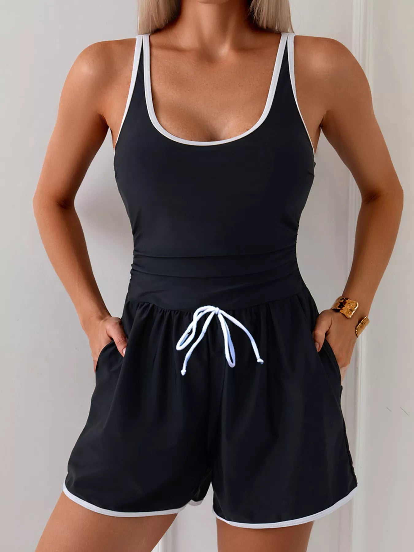 NEWYORKLISTED STYLE COLLECTION: Person wearing a black tank top and shorts with white trim against a plain background