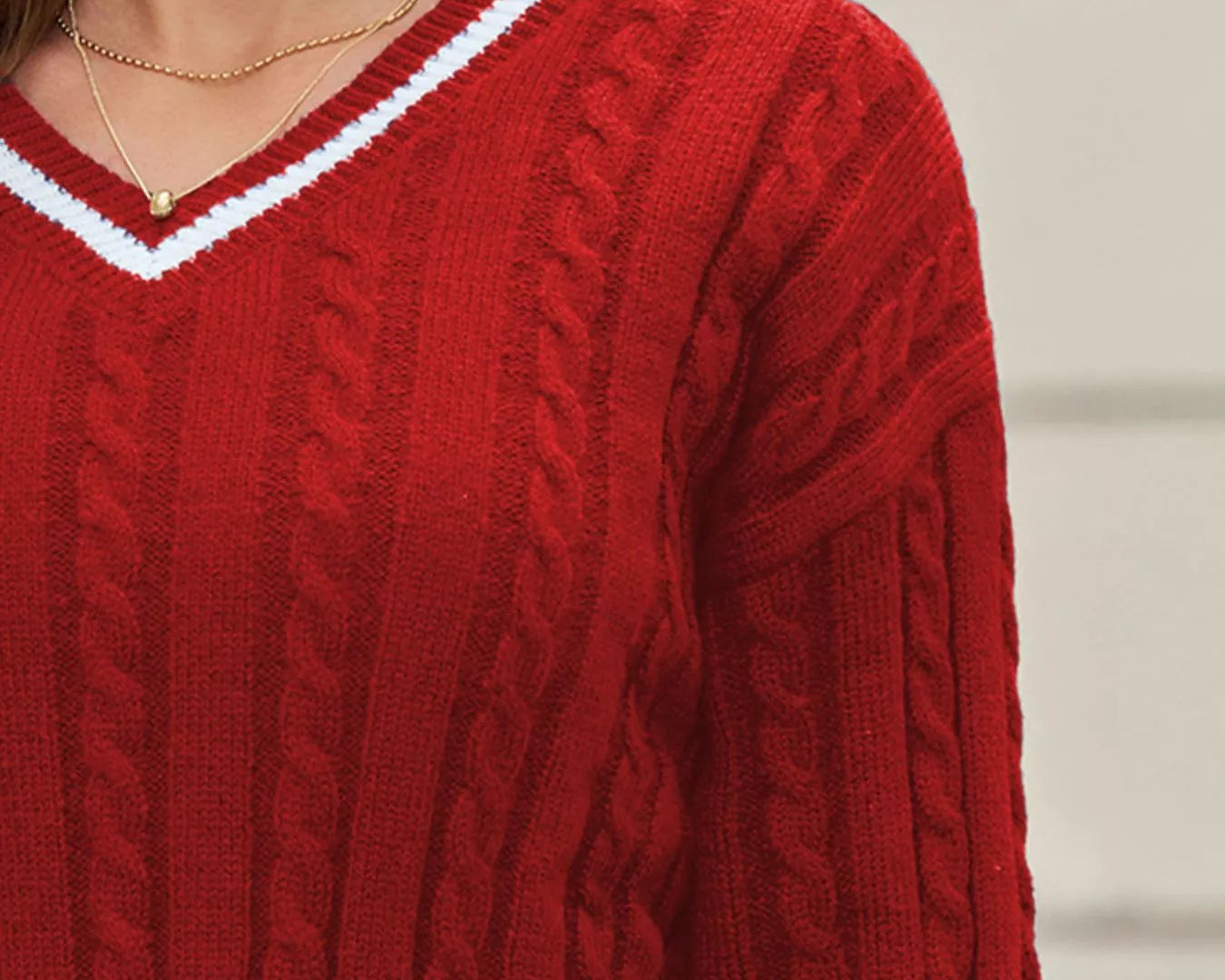 NEWYORKLSITED STYLE COLLECTION: Close-up of a person wearing a red cable knit sweater with a blurred background