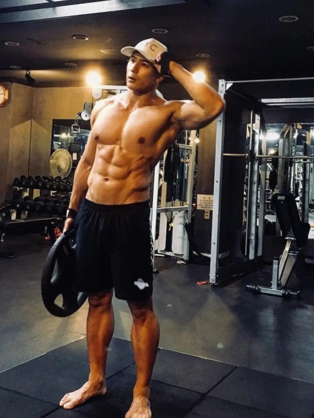 NEWYORKLISTED ATLAS MEN's COLLECTION: Muscular man posing in a gym holding a disc wearing NEWYORKLISTED ATLAS shorts