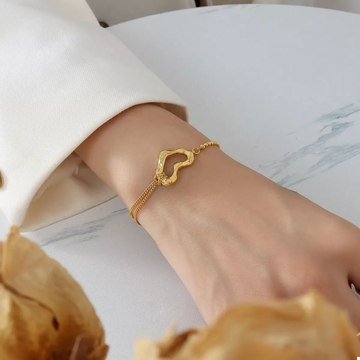 NYLD Glamour Collection by NEWYORKLISTED: Gold bracelet on a wrist with a blurred background