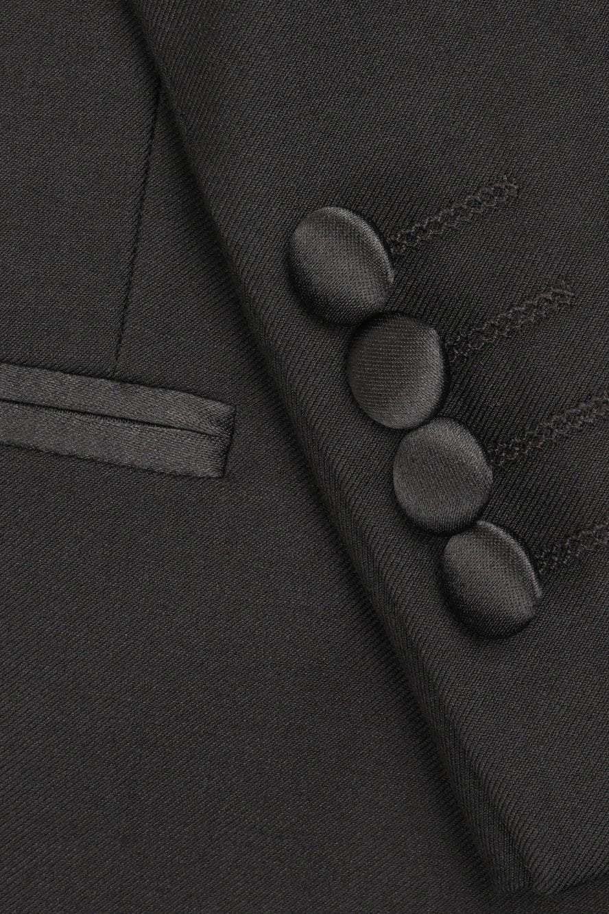 Close-up of a dark gray suit jacket with buttons and a lapel.