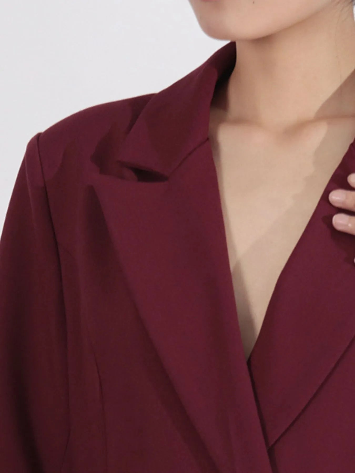 NEWYORKLISTED Runway Style: Close-up of a burgundy blazer worn by a person on a white background