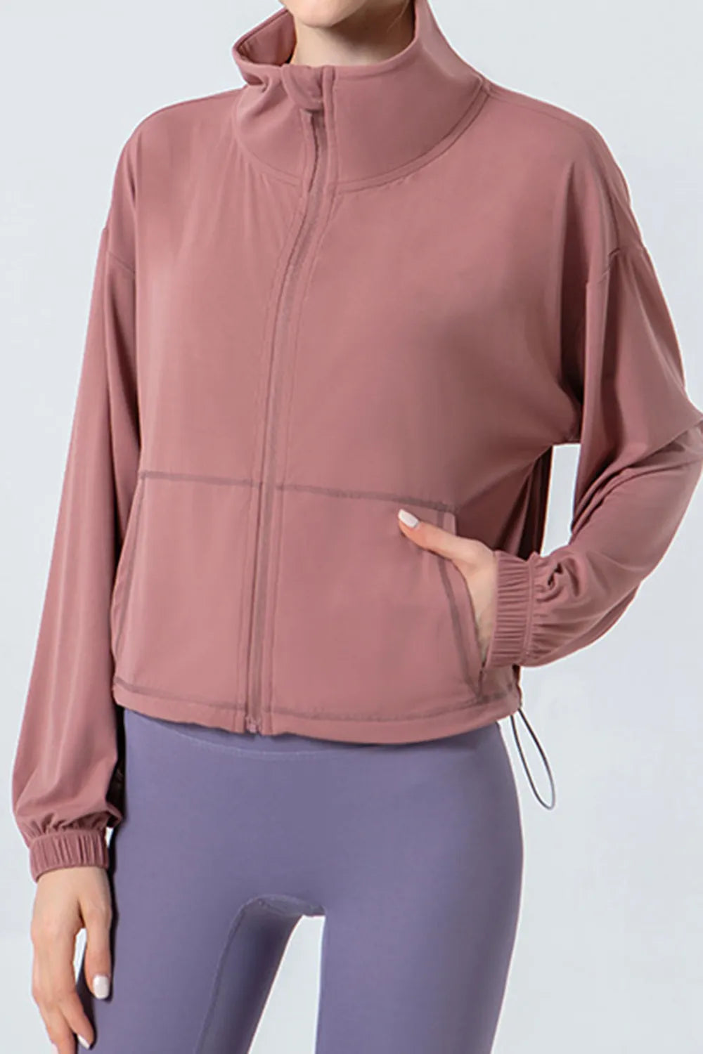 NEWYORKLISTED ACTIVEWEAR COLLECTION: Person wearing a pink jacket and purple leggings on a light gray background