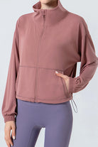NEWYORKLISTED ACTIVEWEAR COLLECTION: Person wearing a pink jacket and purple leggings on a light gray background
