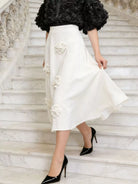 NEWYORKLISTED STYLE COLLECTION: Person wearing a white skirt with floral embellishments on marble stairs