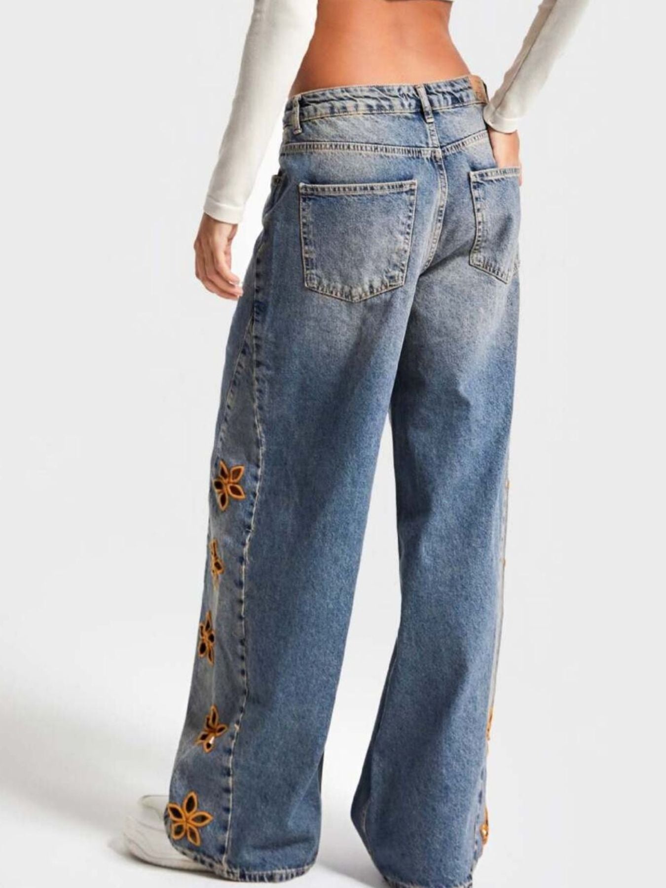 NEWYORKLISTED STYLE COLLECTION: Blue jeans with floral embellishments on a white background