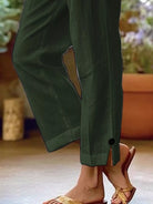 NEWYORKLISTED STYLE COLLECTION: A close-up of a person wearing dark olive green wide-leg pants with a side slit and a small black button detail near the hem, paired with gold-toned slide sandals.